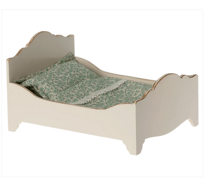 A small white Maileg Wooden Bed in Mouse made of wood, featuring green patterned bedding with Maileg printed fabrics, ensures a good night's sleep for your little one's favorite doll.