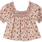 The Girls’ Ada Blouse by Rylee & Cru, featuring a red and beige floral print, short sleeves with puffed shoulders, an A-line silhouette, and a smocked square neckline, is laid flat on a white background.