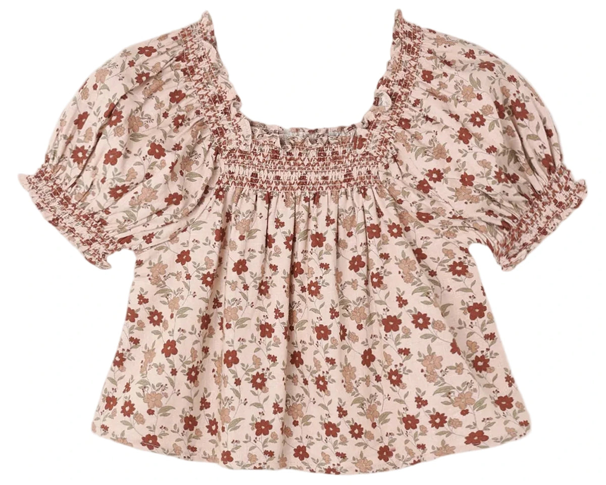 The Girls’ Ada Blouse by Rylee & Cru, featuring a red and beige floral print, short sleeves with puffed shoulders, an A-line silhouette, and a smocked square neckline, is laid flat on a white background.