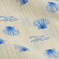 Close-up of cream-colored fabric from the Arsene & Les Pipelettes Baby Girls' Felixia Top, showcasing blue embroidered seashells and wavy lines.