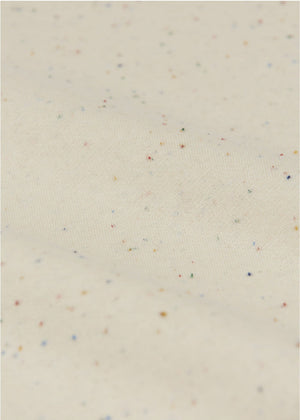 Close-up of cream-colored fabric with multicolored specks and gentle folds, showcasing the soft texture of Arsene & Les Pipelettes Baby Gabano Speckled Joggers.