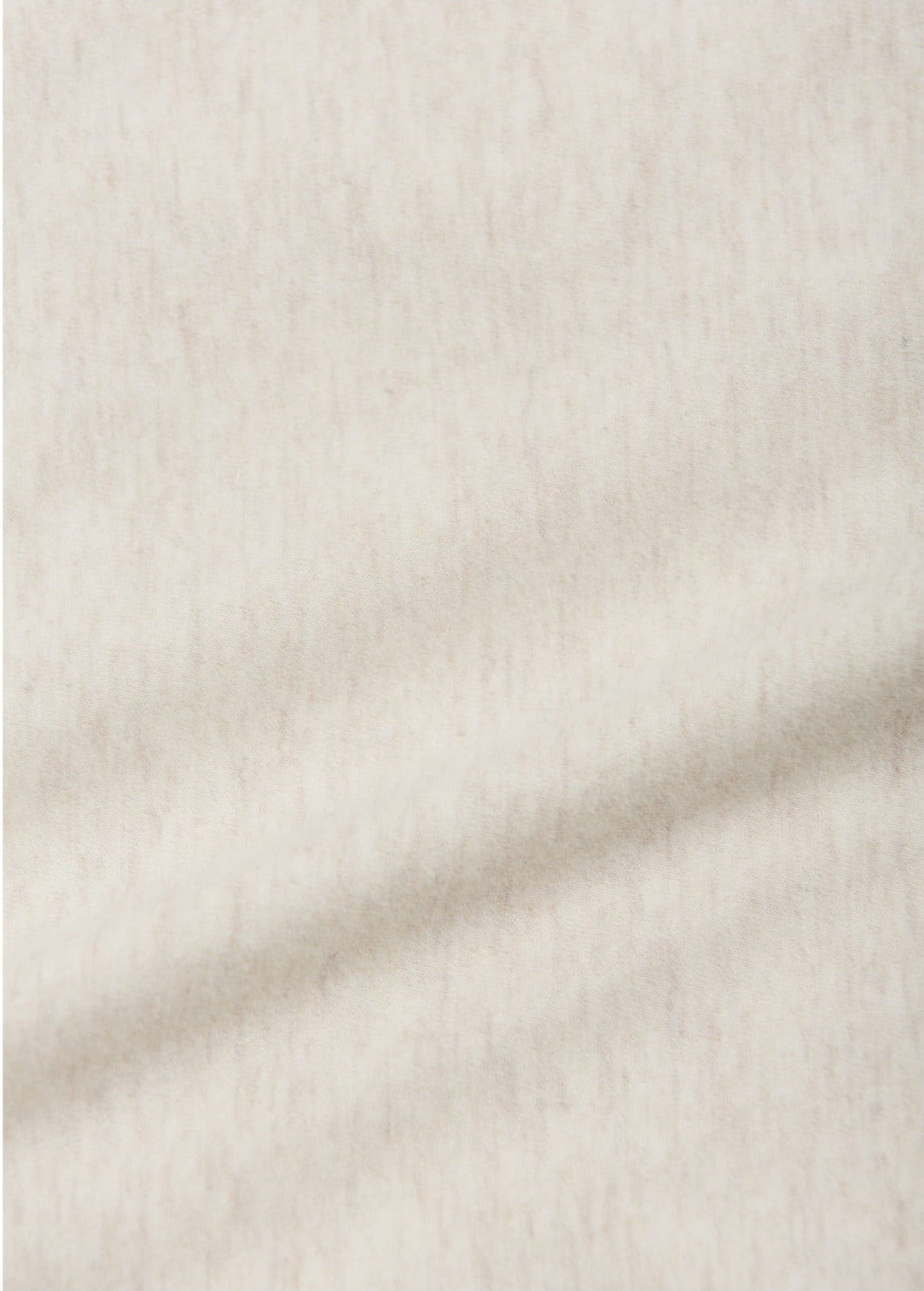 Close-up of the soft, light beige fabric used in the Arsene & Les Pipelettes Baby Golbert T-shirt Cable Car Bio—subtly mottled with a faint diagonal crease, perfect for a cozy baby tee.