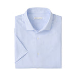 The Peter Millar Baldwin Performance Sport Shirt is light blue, short-sleeve, features a subtle geometric pattern, two-way stretch, and has a label inside the collar.