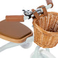Close-up of the Banwood Kids’ Trike, featuring brown leather-like handle grips, a matching seat, a small bell, and a woven wicker basket attached to the handlebars.