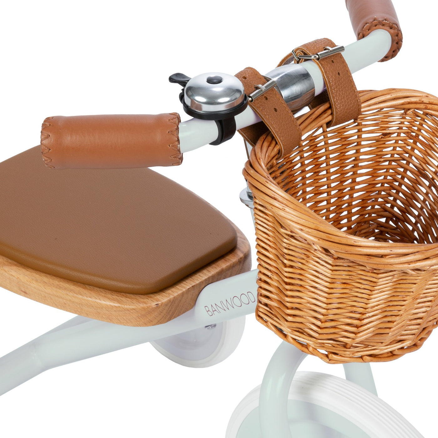 Close-up of the Banwood Kids’ Trike, featuring brown leather-like handle grips, a matching seat, a small bell, and a woven wicker basket attached to the handlebars.