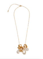 The Cirque Necklace by Lizzie Fortunato features a gold-plated chain adorned with abstract gold, cream, and freshwater pearl-like pendants clustered near the center, displayed against a white background.