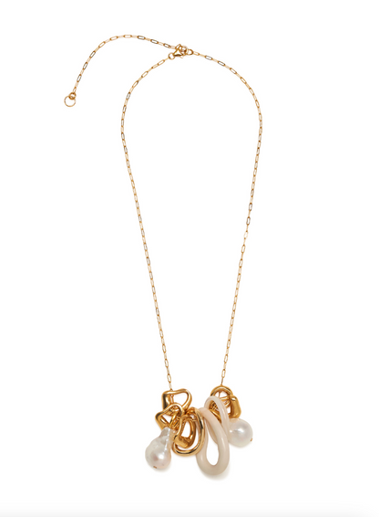 The Cirque Necklace by Lizzie Fortunato features a gold-plated chain adorned with abstract gold, cream, and freshwater pearl-like pendants clustered near the center, displayed against a white background.