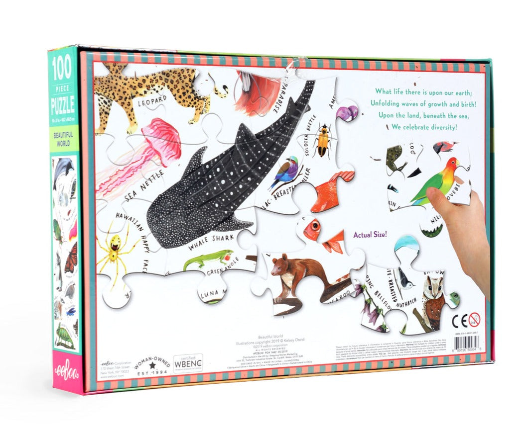 Box of the eeboo Beautiful World 100 Piece Puzzle, by Eeboo, an educational jigsaw that showcases diverse fauna such as sea nettles, a whale shark, and a leopard. The scattered pieces come together to unveil a phrase celebrating earthly wonders.