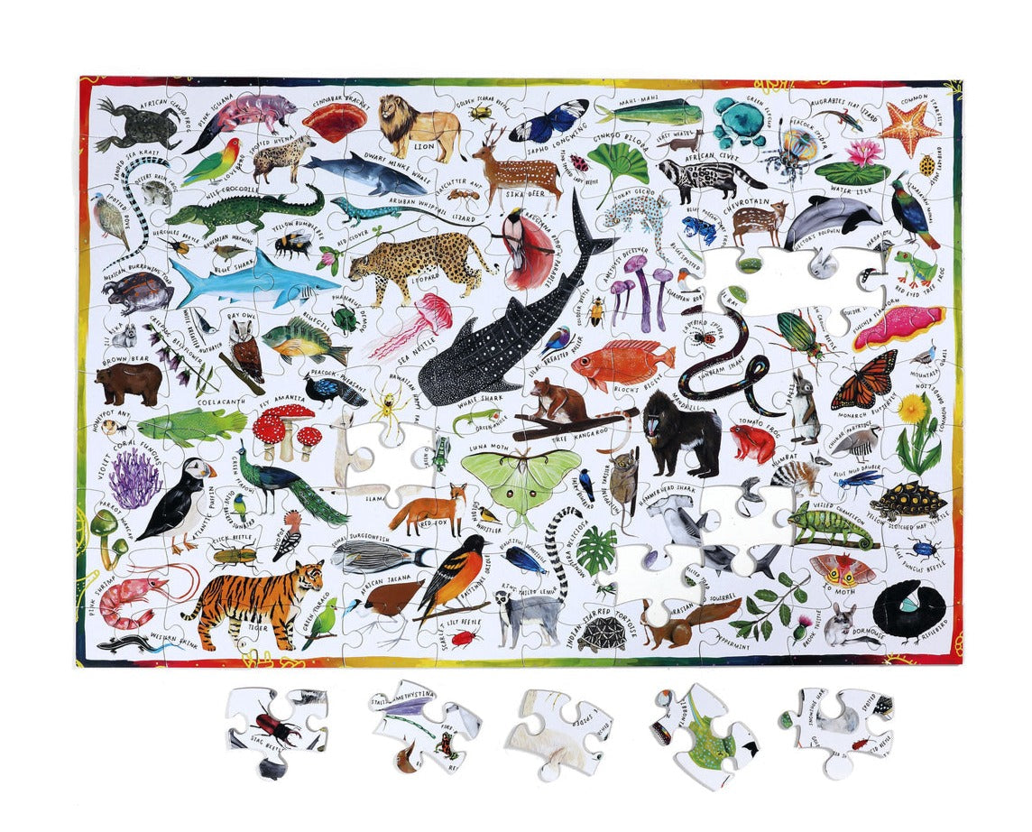 The eeboo Beautiful World 100 Piece Puzzle by Eeboo is a vibrant and educational jigsaw, highlighting an impressive collection of animals, plants, and sea creatures. Positioned below the puzzle are several pieces that display the detailed flora and fauna ready to be explored.