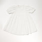 Early Sunday Girls’ Beth Dress in ivory, featuring short sleeves, a high collar, a gathered waist, and subtle embroidered cotton details, laid flat on a plain background.