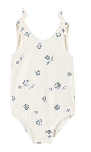 The Baby Girls' and Girls' Mille One-Piece by Rylee & Cru is a white sleeveless swimsuit with a blue seashell print and shoulder ties, shown on a plain background.