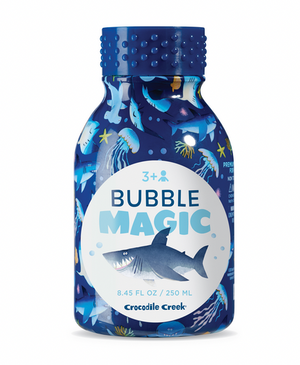 A blue Bubble Magic bottle by Crocodile Creek, decorated with shark and ocean designs—ideal for outdoor bubble play. Suitable for ages 3+ and holds 250 mL; perfect with bubble wands for endless fun.