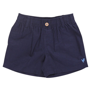 The Boys’ Jackson Short by Pink Chicken features navy blue cotton canvas, an elastic waistband, button closure, belt loops, and a small embroidered rooster on the left leg.