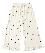 The Girls' Wide Leg Pant by Rylee & Cru, shown laid flat on a plain background, features a comfortable wide-leg silhouette in white with black polka dots, an elastic drawstring waist, and ruffled hems at the ankles.