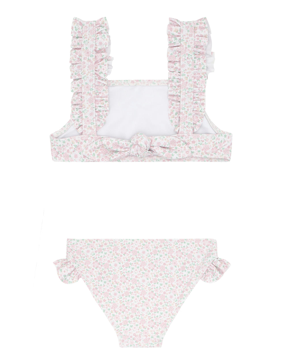 The Minnow Girls' Ruffle Strap Bikini in Antique Floral by Minnow features a chic square-neck top with ruffled wide straps and an adjustable back tie for a perfect fit, along with the bottoms having elegant ruffled detailing on the sides. The fabric boasts a subtle pink floral design that enhances its vintage charm.