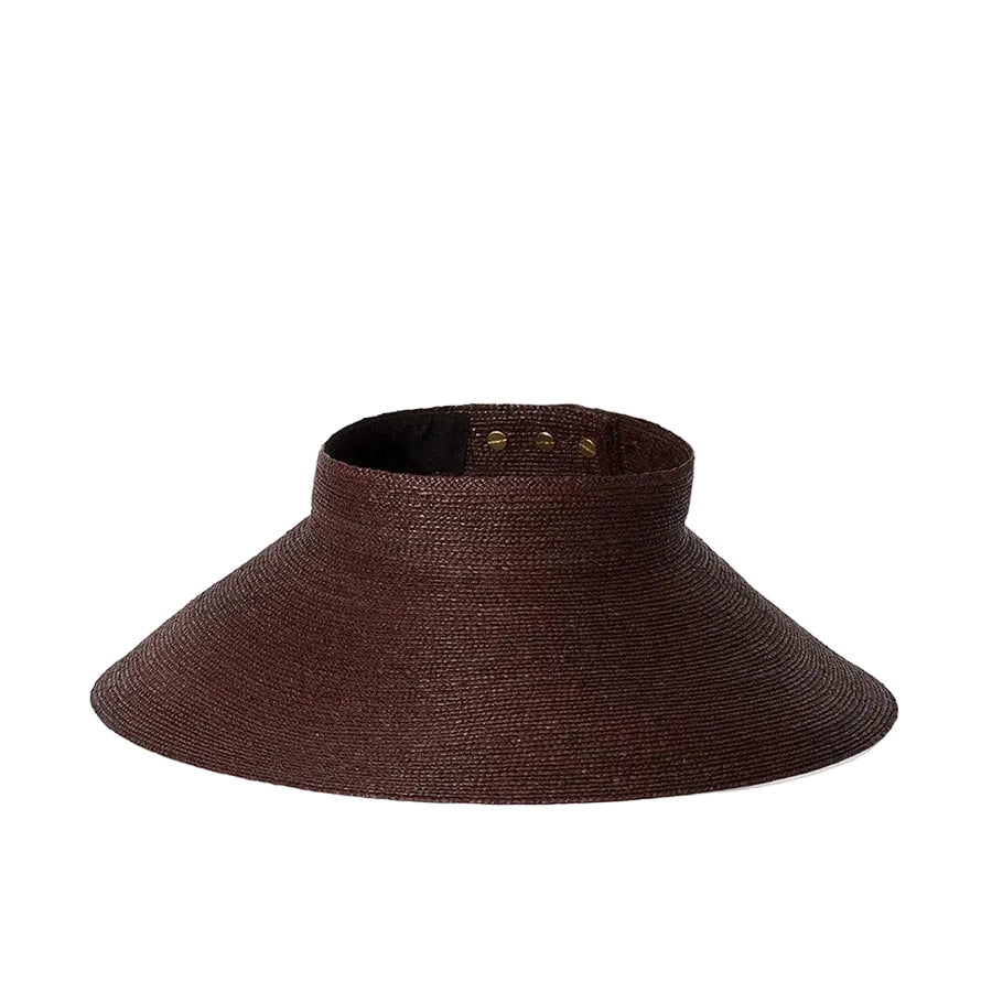 The Birdie Visor by Janessa Leone is a wide-brimmed brown raffia straw visor with an open top and adjustable back strap, shown on a plain white background.