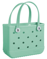 A mint green Bitty Bogg Bag from Bogg Bags, featuring perforated sides and two sturdy handles with button closures embossed with the letter "b". This lightweight EVA bag is perfect for carrying all your essentials with ease.