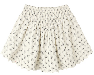 The Girls’ Smocked V Mini Skirt by Rylee & Cru features a smocked waistband, scalloped hem, and a delicate small black floral print on lightweight fabric. This timeless silhouette effortlessly blends comfort and style for an elegant look.