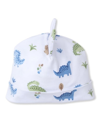 The Kissy Kissy Baby Dinosaur Novelty Hat is a soft white Pima cotton hat with a playful top knot, decorated with blue and green dinosaurs and leafy plants.