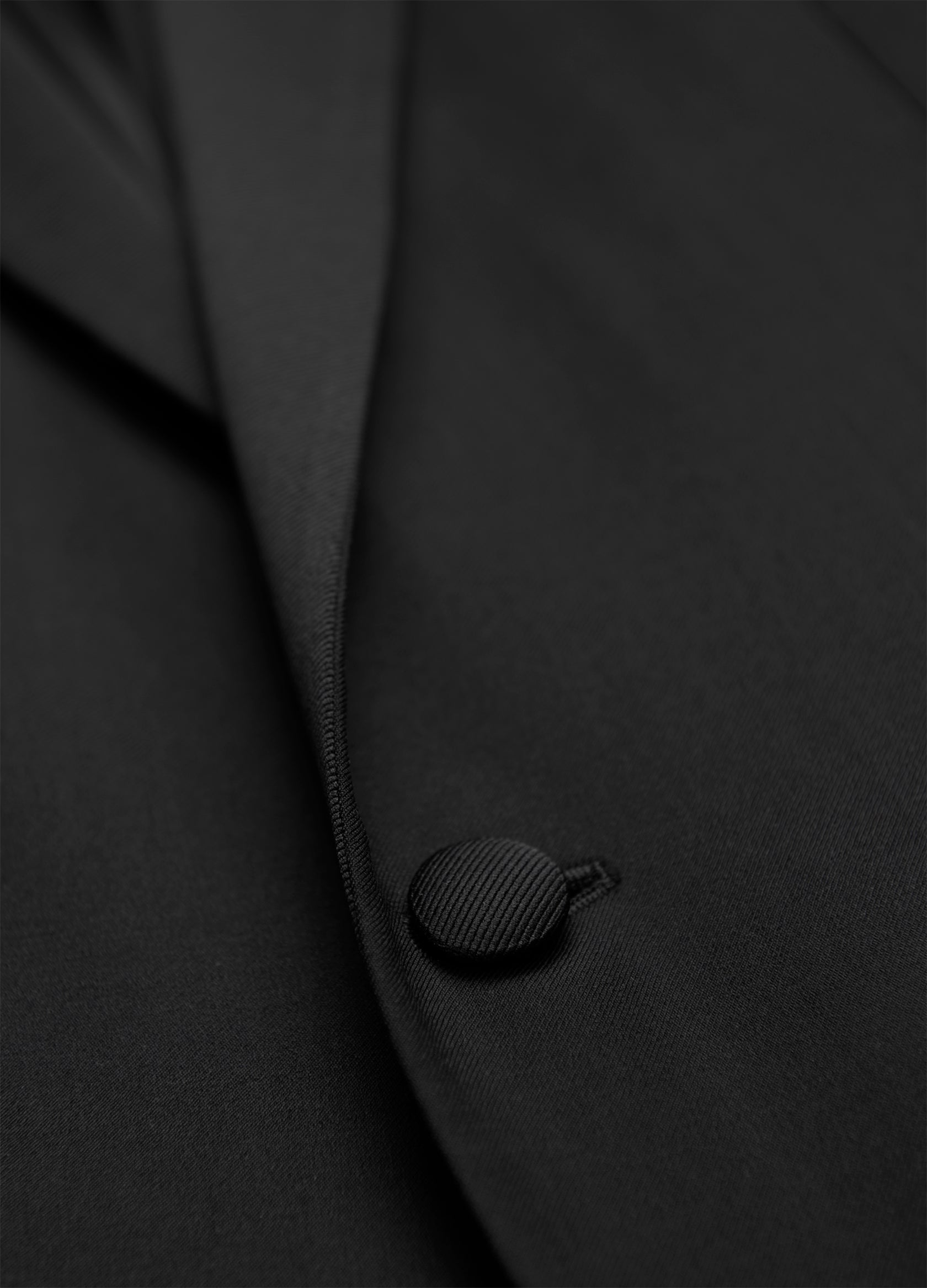 Close-up of a Samuelsohn Garner Classic Fit Tuxedo in black, crafted from luxurious Super 150's fabric, highlighting a single button and a section of the lapel—ideal for any formal occasion.