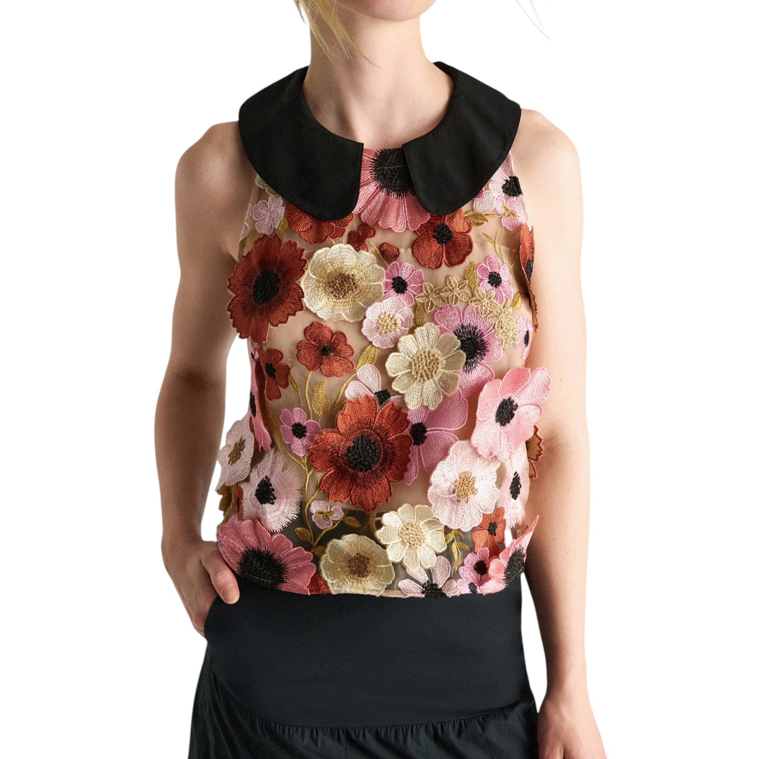 A woman wears the Dorothee Schumacher Blooming Meadow Top, featuring floral 3D embroidery and a black Peter Pan collar, styled with a black skirt.
