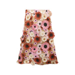 The Blooming Meadow Skirt by Dorothee Schumacher is an A-line midi skirt with a pink mesh overlay decorated with couture-inspired 3D floral appliqués in shades of pink, red, white, and beige.