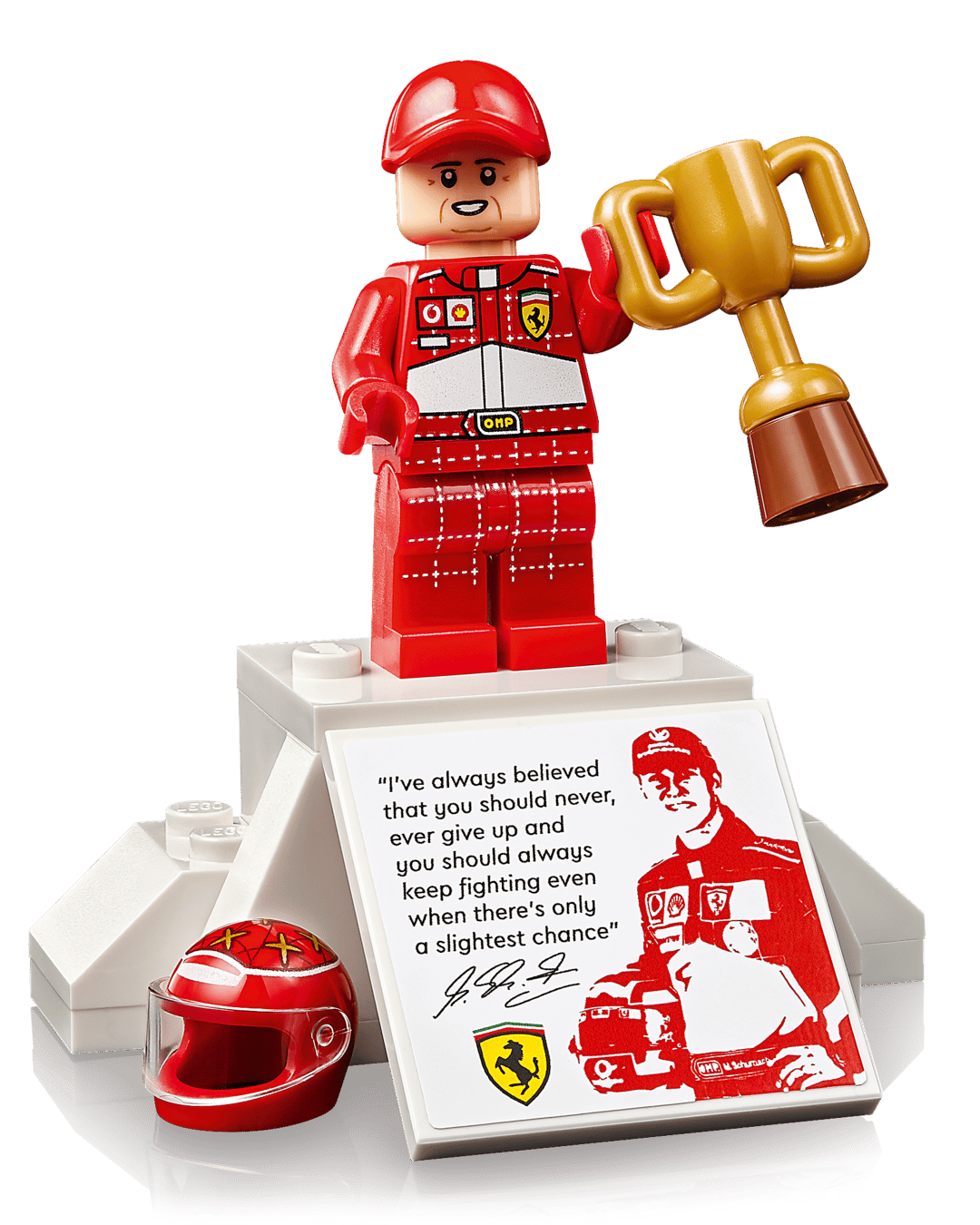 A LEGO® Icons Ferrari F2004 & Michael Schumacher minifigure by Legos - Toyhouse, in a red racing suit, holds a trophy on a podium with a red helmet, quote plaque, and an image of the famous Ferrari F2004 Formula 1 car.