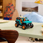 A LEGO® Technic™ Jeep® Wrangler Rubicon SUV by Legos - Toyhouse, with teal and black colors and orange wheels, is displayed on a light green desk in a cozy, well-lit room.