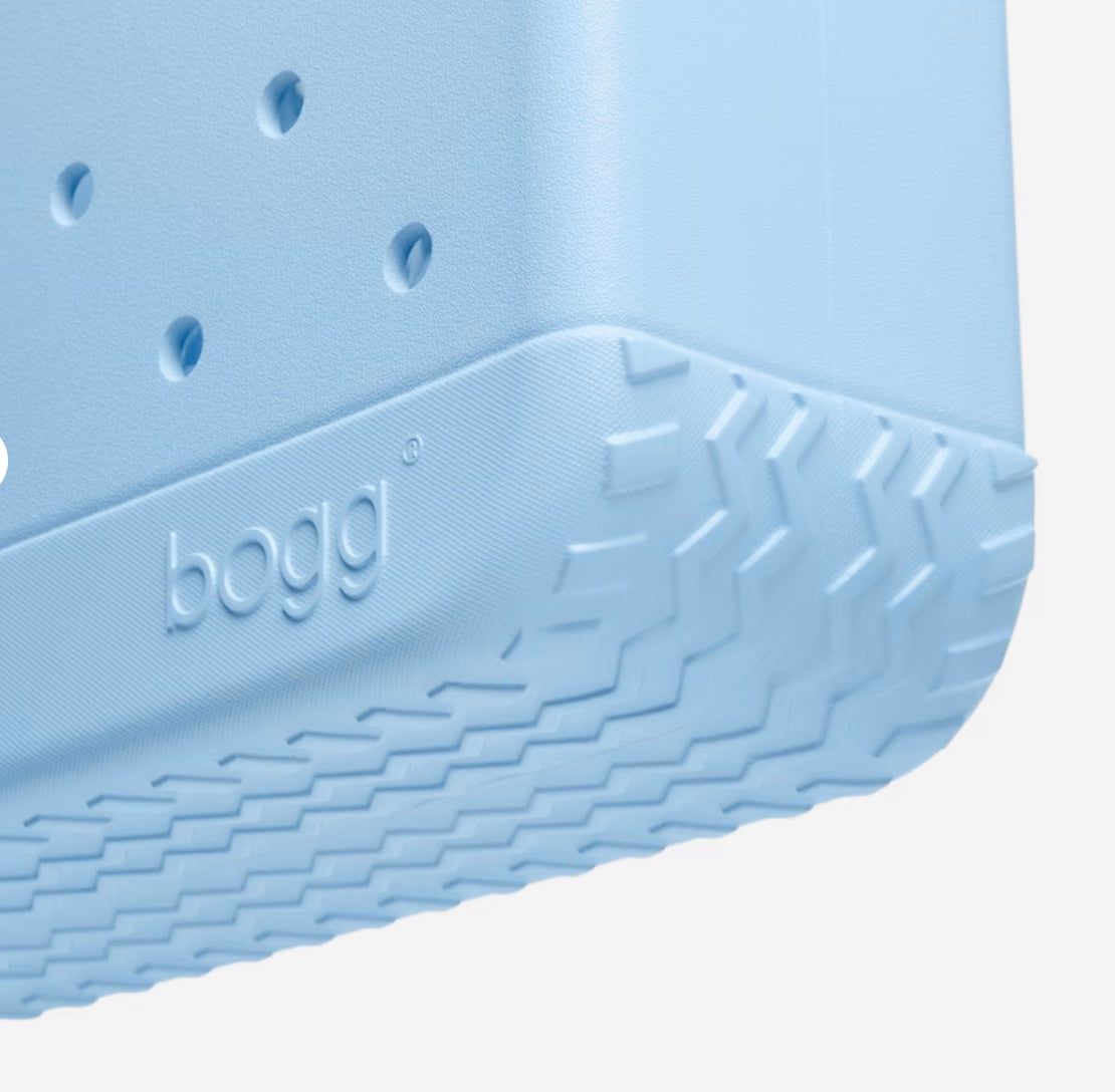 Close-up of a light blue textured plastic item with the word “bogg” embossed; corner and side details are visible, featuring raised chevron patterns and small holes—signature features of the durable Baby Bogg® Bag by Bogg Bags, a washable bag designed for everyday adventures.