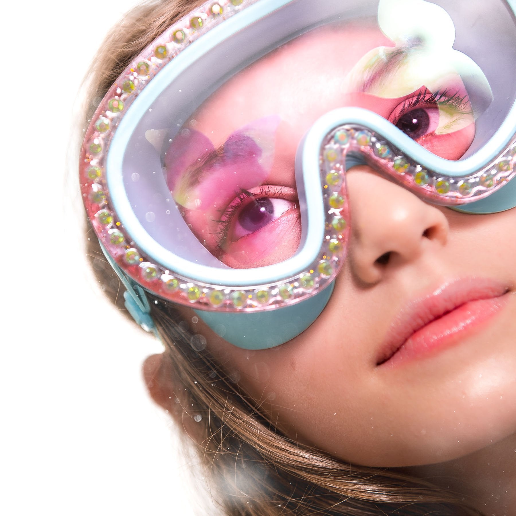 A girl with long hair wears large, decorative goggles with pink-tinted lenses that resemble the stylish Bling2o Blue Sushi Blue Sea Swim Mask by Bling2O as she gazes upwards.