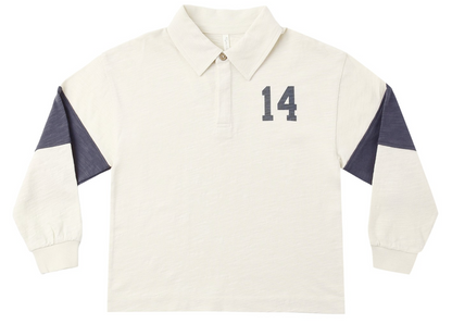 The Rylee & Cru Baby Boys’ and Boys’ Rugby Polo features long sleeves, a cream color, a classic collar with buttoned neckline, navy “14” on the chest, and navy panels on the upper sleeves for a timeless athletic look.