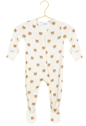 The Baby Teddy Zipper Footie by Lou Lou & Company is a cozy, cream-colored onesie with foot coverings, featuring an all-over brown bear face print. Crafted from silky-soft fabric, it is displayed on a gold hanger.