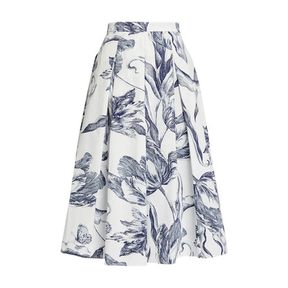 The "Botanical Engraving Pleated Midi Skirt" by Erdem is an ivory cotton poplin A-line skirt adorned with a blue botanical print of large leaves and flowers.