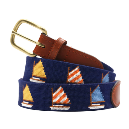 Smathers & Branson's Rainbow Fleet Belt is a navy hand-stitched accessory, featuring sailboat designs in yellow, orange, and blue, complemented by brown Italian leather accents and a brass buckle.