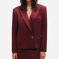 Someone wearing a burgundy Novalis Sunfire Blazer by Blaze Milano with wide lapels and gold buttons, standing against a plain white background.