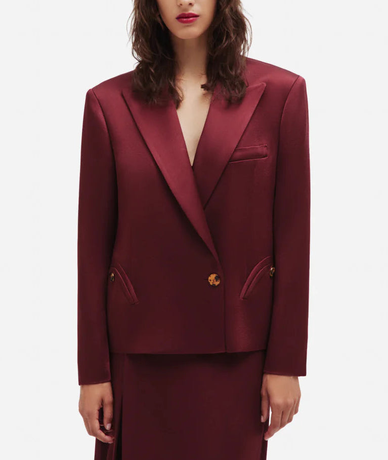 Someone wearing a burgundy Novalis Sunfire Blazer by Blaze Milano with wide lapels and gold buttons, standing against a plain white background.