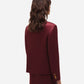 A person with wavy brown hair wears the Blaze Milano Novalis Sunfire Blazer and a matching burgundy satin skirt, shown from the back against a plain white background.
