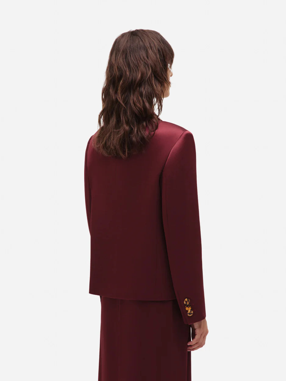 A person with wavy brown hair wears the Blaze Milano Novalis Sunfire Blazer and a matching burgundy satin skirt, shown from the back against a plain white background.