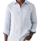 A person wearing the Faherty Laguna Linen Shirt in light blue, featuring a chest pocket and rolled-up sleeves, stands against a white background.