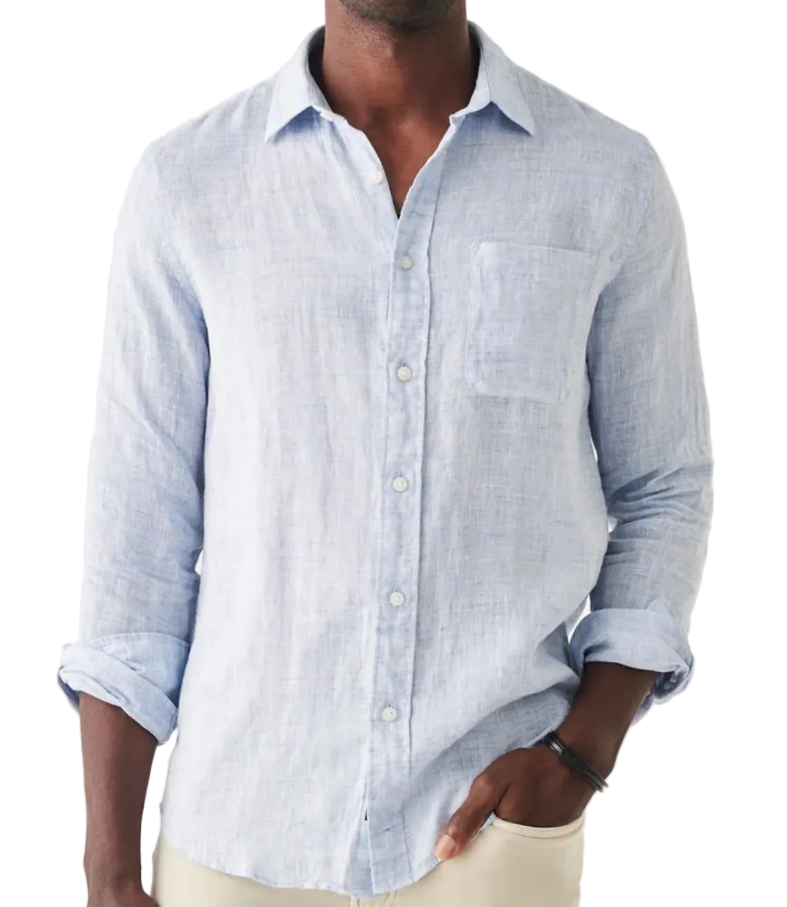A person wearing the Faherty Laguna Linen Shirt in light blue, featuring a chest pocket and rolled-up sleeves, stands against a white background.