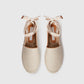A pair of beige Stella McCartney Gaia Canvas Flat sandals with textured canvas, woven soles, and ribbon ankle ties, shown top-down on a white background. Lightweight and stylish.