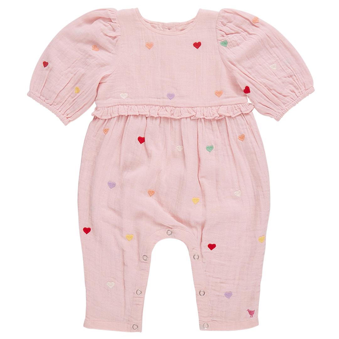 The Pink Chicken Baby Girls' Brooke Jumper features candy heart embroidery on a pink romper with puff sleeves, multicolored heart patterns, and waist ruffle detailing, designed for easy diaper changes.