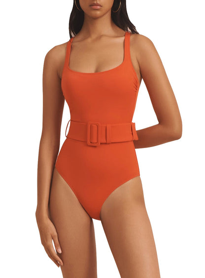 A person wearing the Evarae Cassandra One Piece, an orange swimsuit featuring a belted waist and a square neckline.