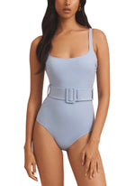 A person wearing the Evarae Cassandra One Piece swimsuit in light blue, featuring a square neckline and a belted waist, made through sustainable manufacturing practices.