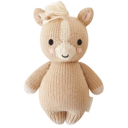 Meet the Baby Pony by Cuddle + Kind—a beige, hand-knitted stuffed animal crafted from extra soft cotton yarn, featuring a smiling face, round body, upright ears, and a cream-colored mane. This adorable pony is the perfect soft baby toy or cherished heirloom for years to come.
