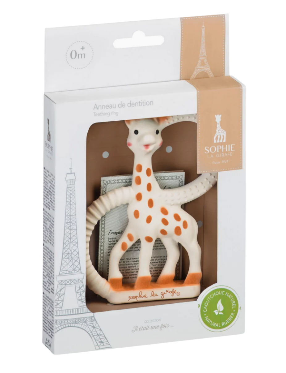 The boxed Teething Ring from Sophie la Girafe, suitable for 0+ months, is made of natural rubber with a giraffe design featuring orange spots. Its textured surfaces offer soothing relief, while the packaging includes an elegant Eiffel Tower illustration, making it perfect for babies.