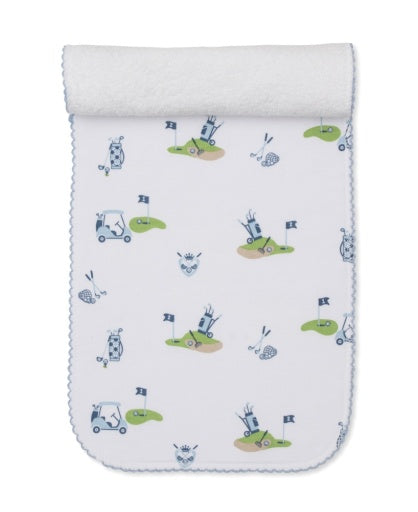 The Kissy Kissy Golf Championship Burp Cloth is crafted from white Pima cotton and features blue and green golf-themed prints—carts, clubs, flags, balls—and a charming blue scalloped trim.