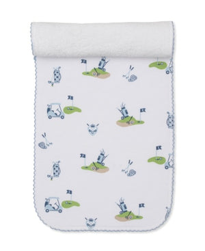 The Kissy Kissy Golf Championship Burp Cloth is crafted from white Pima cotton and features blue and green golf-themed prints—carts, clubs, flags, balls—and a charming blue scalloped trim.