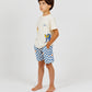 A barefoot child, hands in pockets, stands against a plain light background wearing a cream graphic T-shirt paired with Arsene & Les Pipelettes Boys' Checkered Terry Bermuda Shorts.