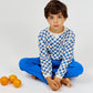 A boy sits cross-legged on the floor wearing the Arsene & Les Pipelettes Boys' Checkered Terry Cloth Sweatshirt and blue pants, with three oranges placed beside him on a white background.